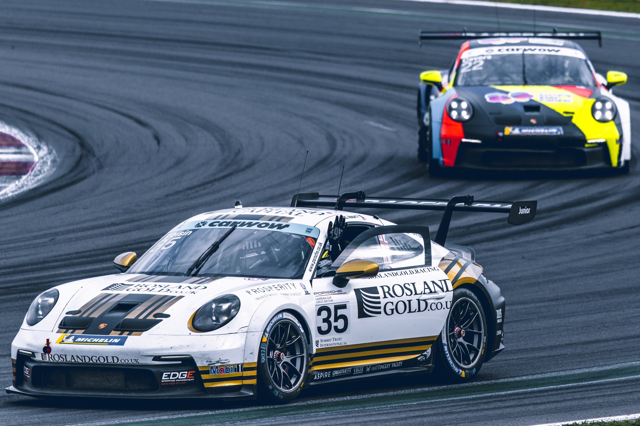White number 35 Porsche leading a second Porsche through a corner.